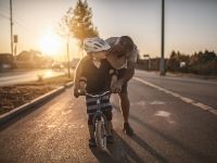 adult teaching a child to ride a bike