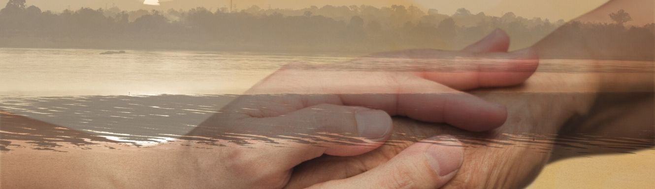 Two pair of hands grasping layed over a transparent picture of a river.