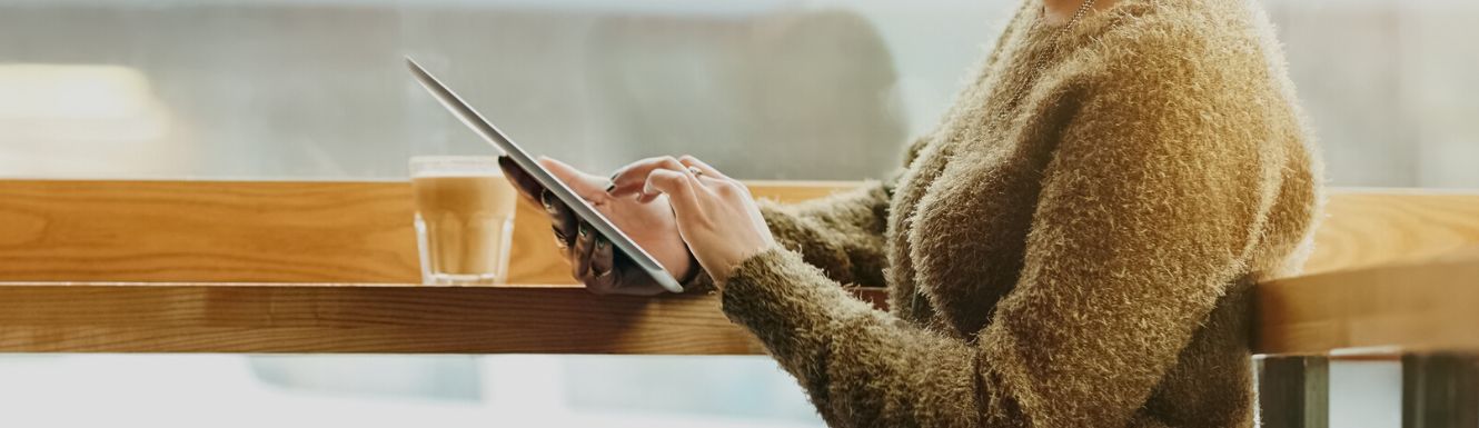 person typing on their tablet while at a coffee shop