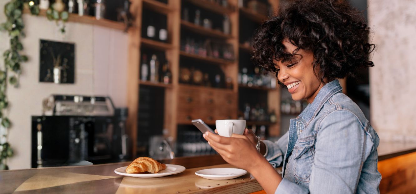 Picture of lady at coffee shop drinking coffee and review her phone.