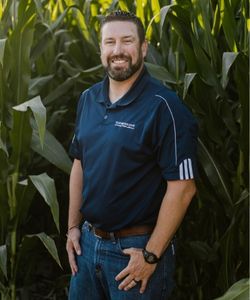 Bret Tiller, Vice President of Lending, standing in front of cornstalks