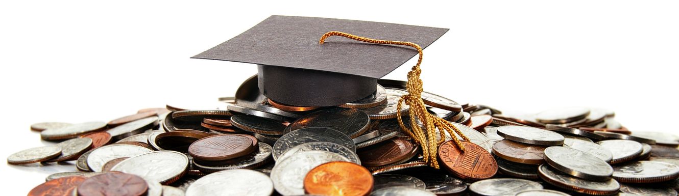 black graduation cap on top of a pile of US currency