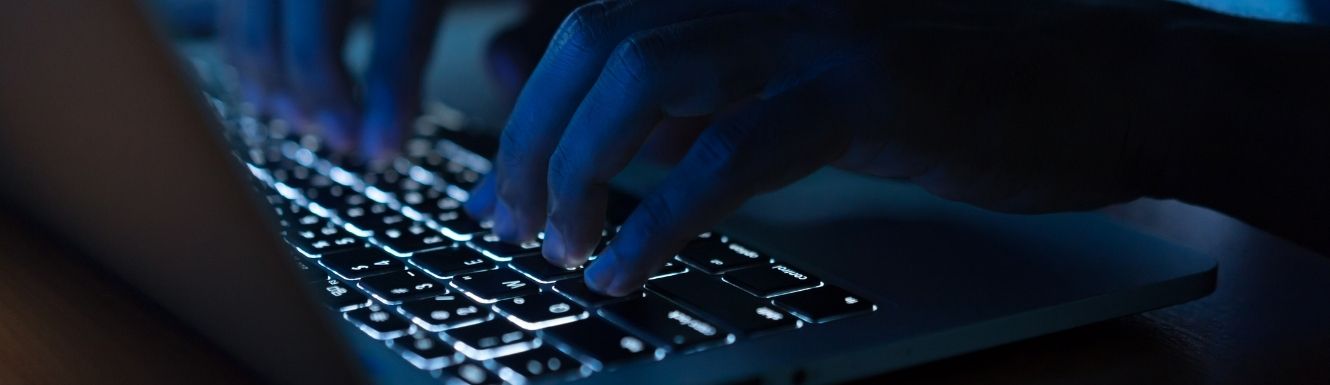 close up image of person typing on laptop in the dark