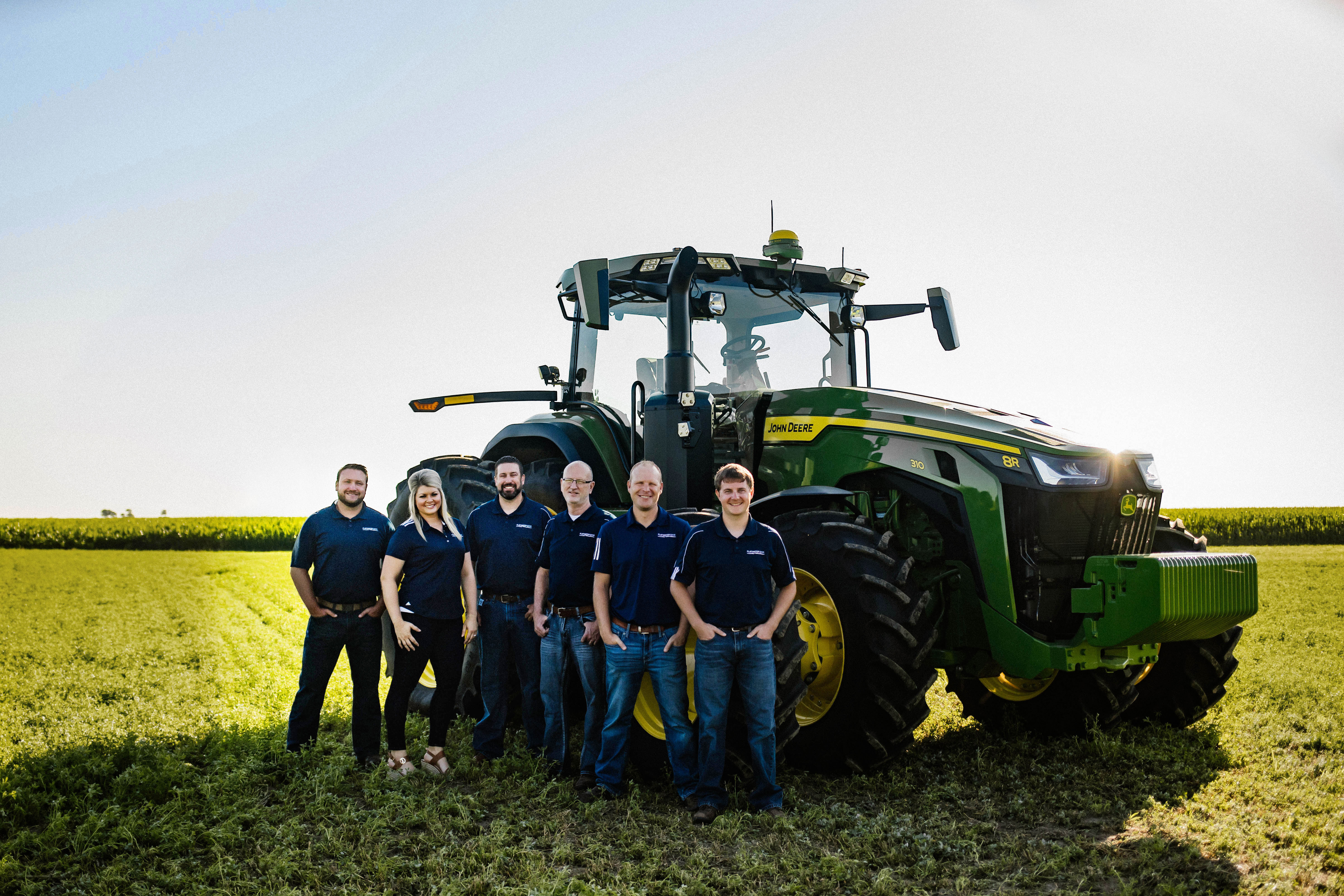 Flatwater Bank loan officers standing in field in front of John Deere tractor - updated 2025