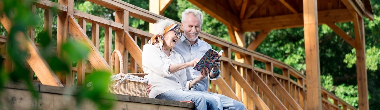 mature couple laughing and sitting on a bridge over the water