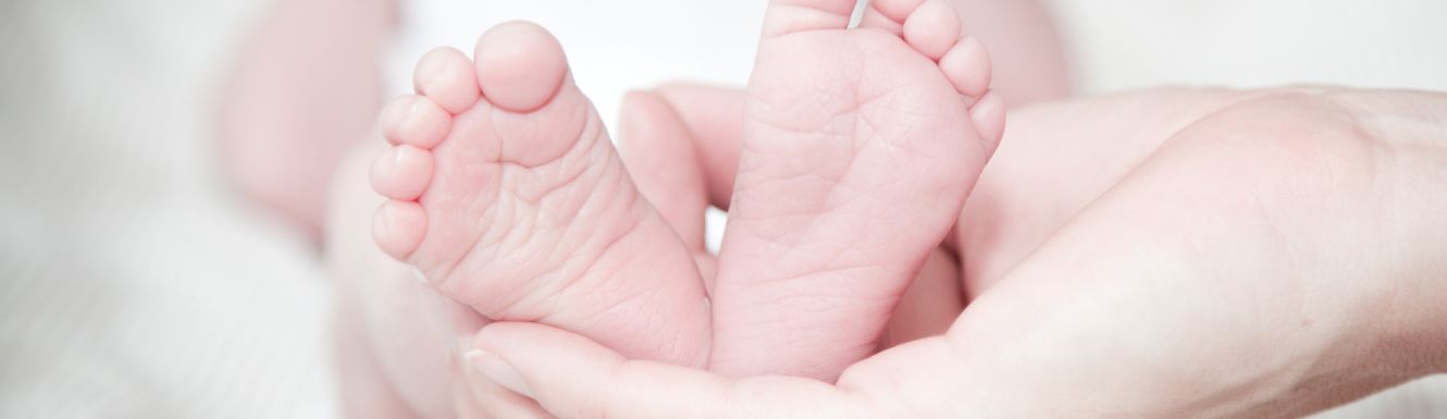 newborn baby's feet being held by a parent's hand