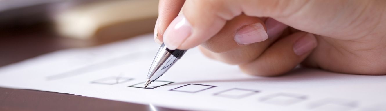 hand holding a pen checking a square box on paper