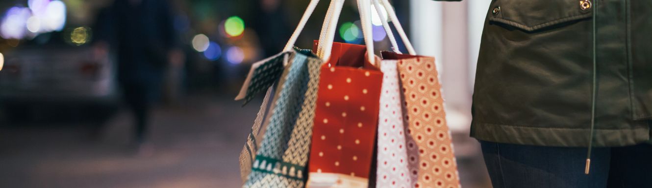 person holding three Christmas shopping bags outside