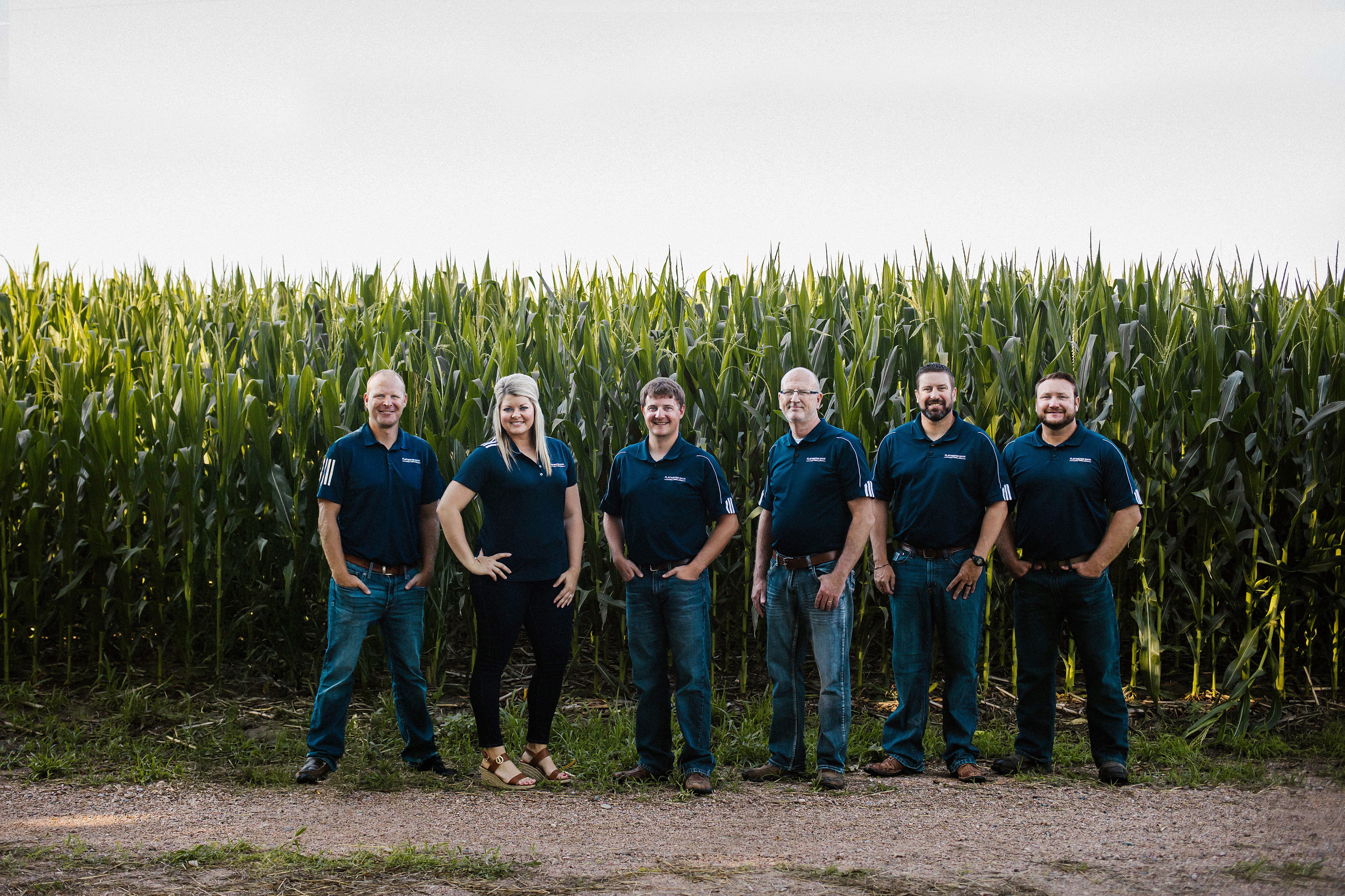 Flatwater Bank loan officers standing in field in front of corn field