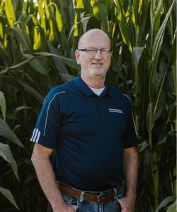 Monty Schriver, Vice President of Compliance, standing in front of cornstalks