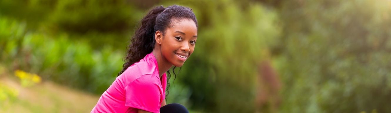 Woman in a pink stop stopped from her run to tie her shoe