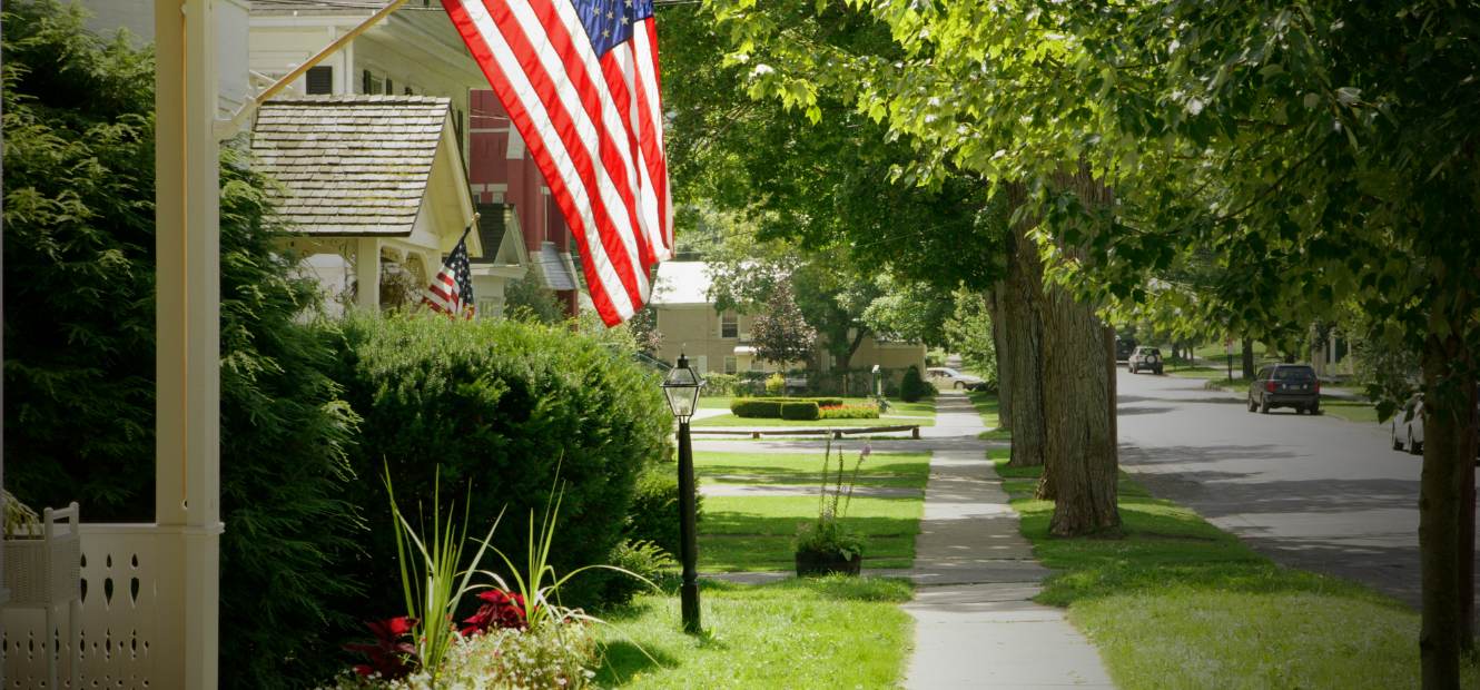Picture of a tree-lined street with flags in front of the houses