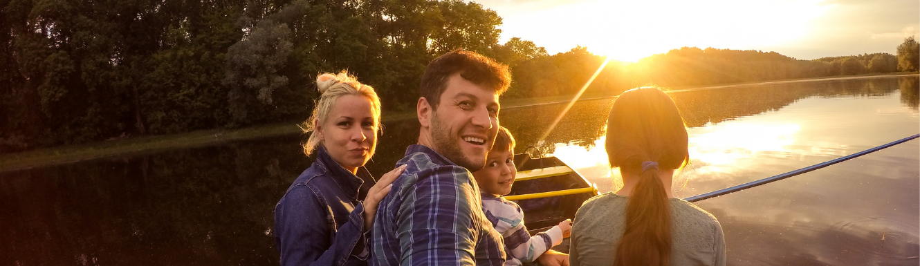 Two parents and their two children fishing on a boat in a lake at sunset
