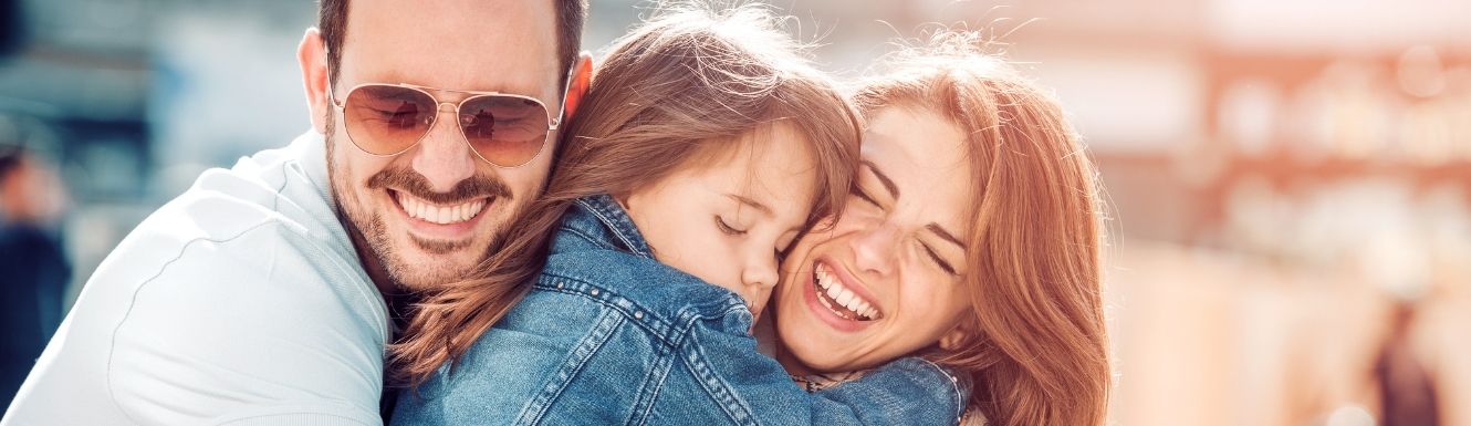 Dad, mom, and daughter hugging and smiling